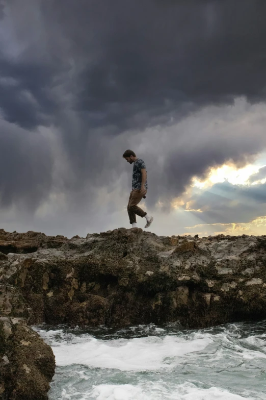 a man is jumping on a rock over the ocean