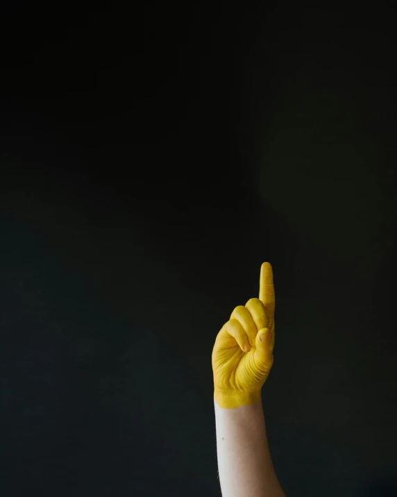 the man is holding his fingers up with yellow paint
