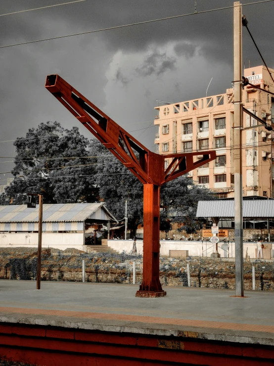 a big old red wooden crane with buildings in the background