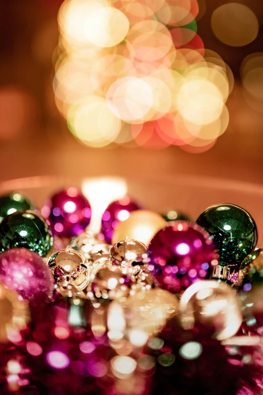 a pink glass christmas ball in front of a boket of lights