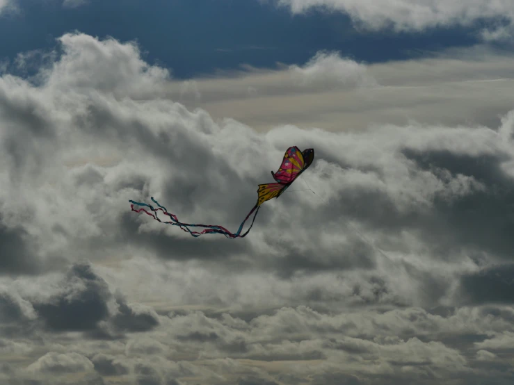 a kite flying through the cloudy sky in front of some clouds