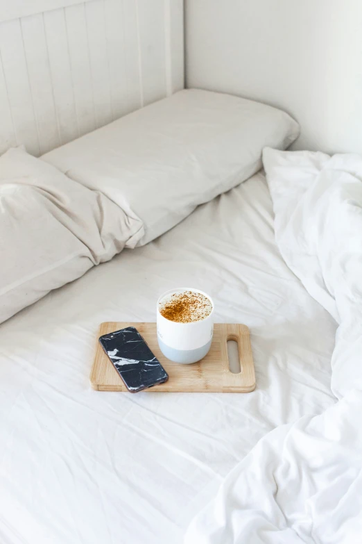 the small cup on a tray is next to a phone
