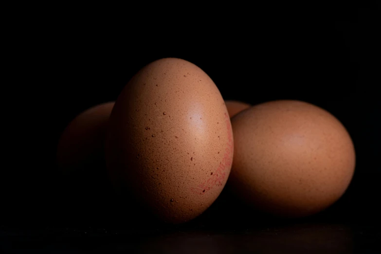 three eggs are in front of a black background