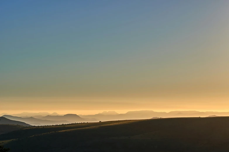 the sun is setting in the horizon over the mountains