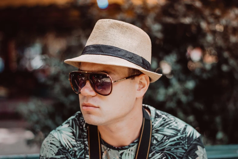 a man wearing sunglasses and a hat looks straight ahead