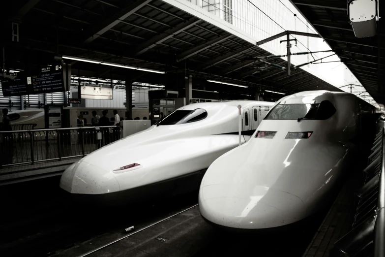 two white trains stopped at a station in japan
