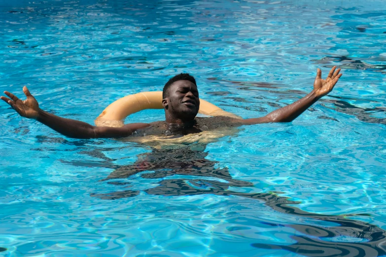 a man swimming in the blue pool holding an item