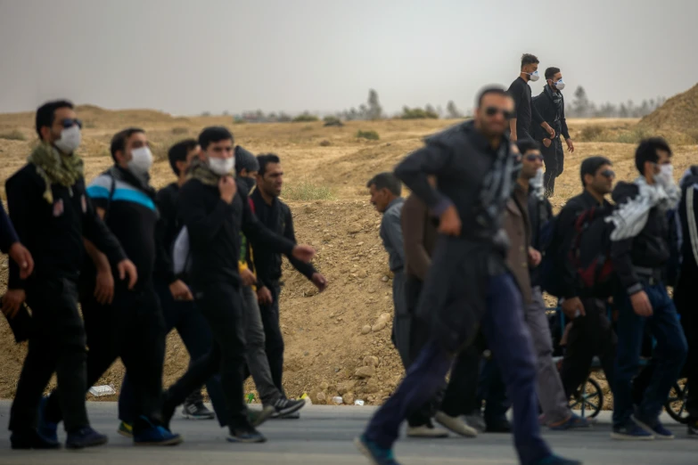 a group of men with face masks on walking down a road