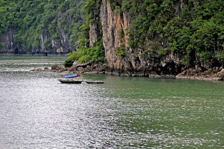 two boats floating along the shore of a lake