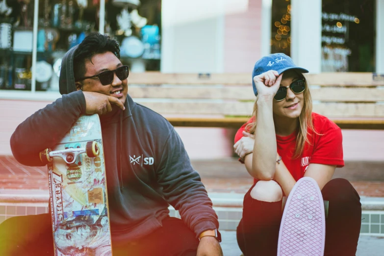 two people posing next to each other holding skateboards