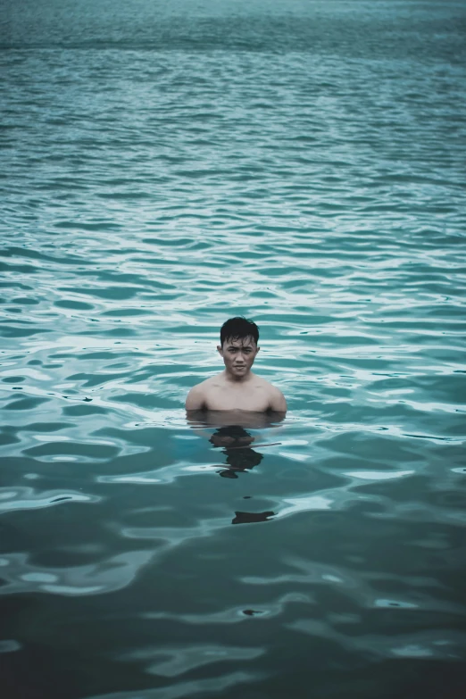 a man swimming through the water with an ocean in the background