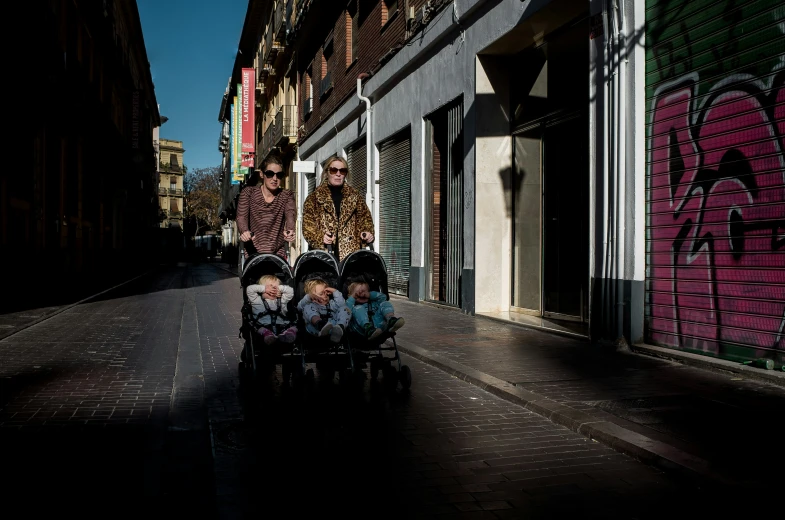 a man in plaid shirt hing two babies in buggies