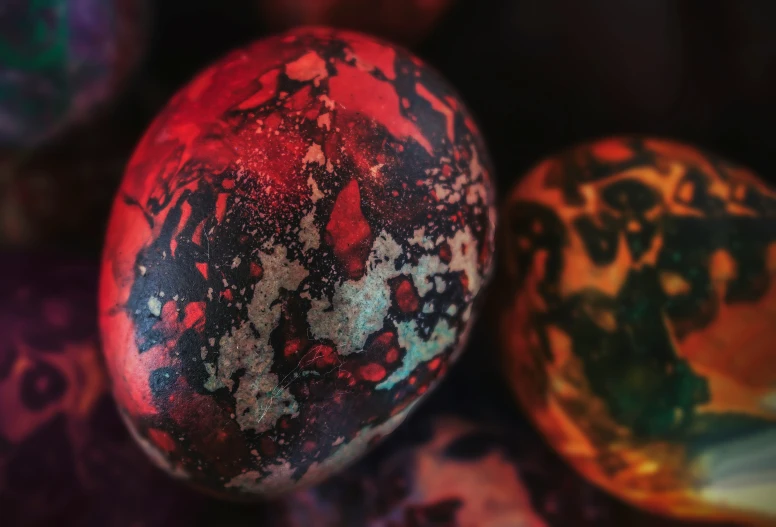 some kind of artistic painted egg sitting in front of colorfully colored ones