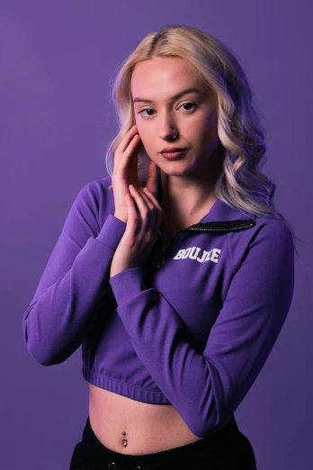 a young blonde woman posing against a purple background