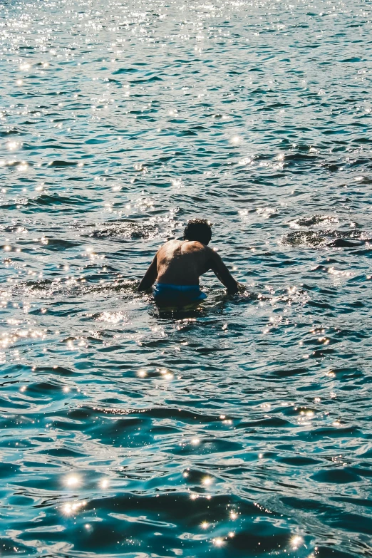 a young man wading into the water to go swimming