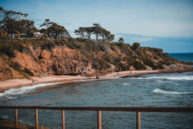 a view from a bridge of a beach and rocky cliff