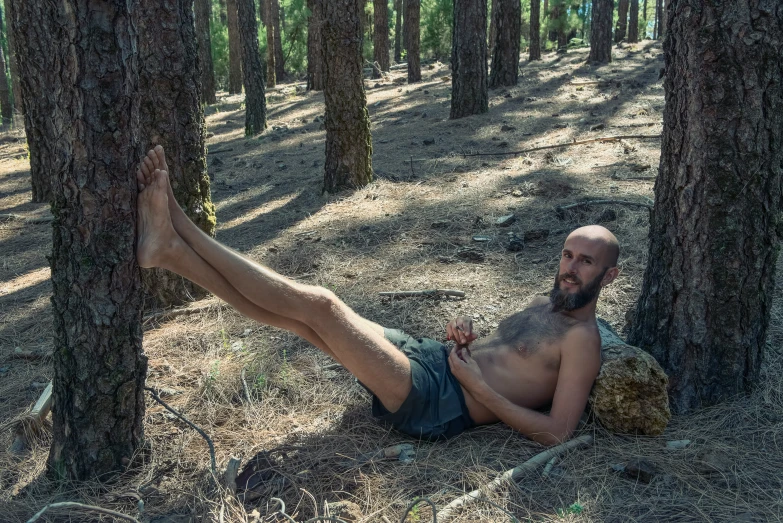 a man in the woods with his feet up laying on a rock