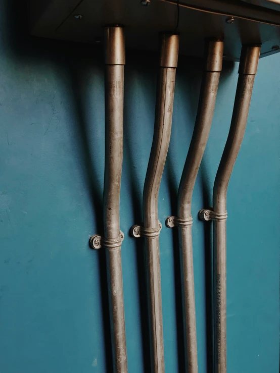 metal pipes hang in a row next to a blue wall