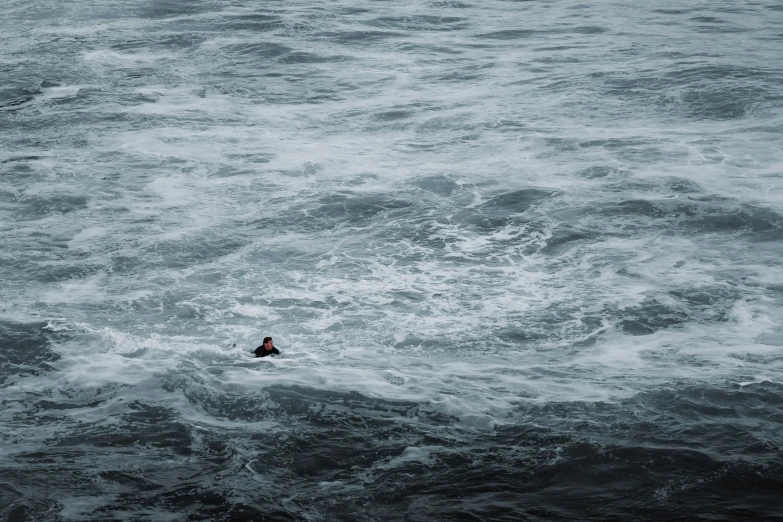 a man paddles through the middle of rough water