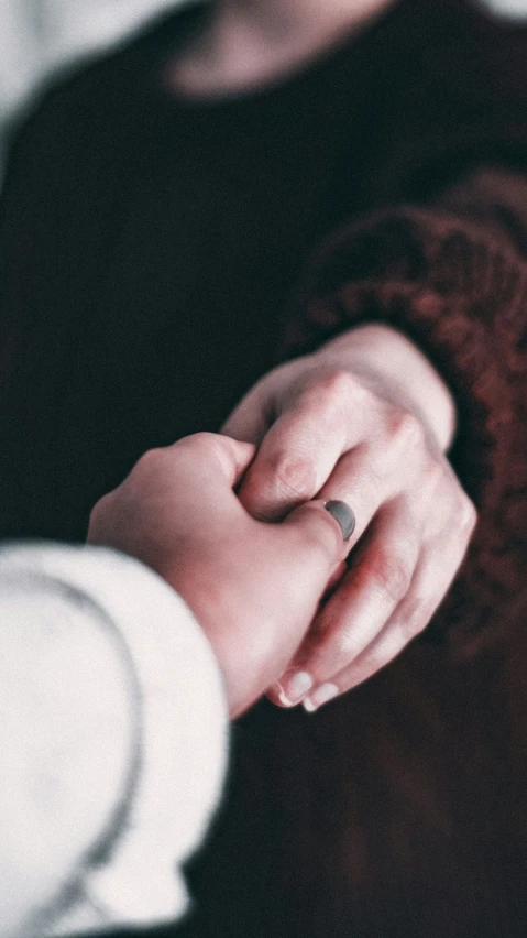 a woman holding another mans hand with both hands