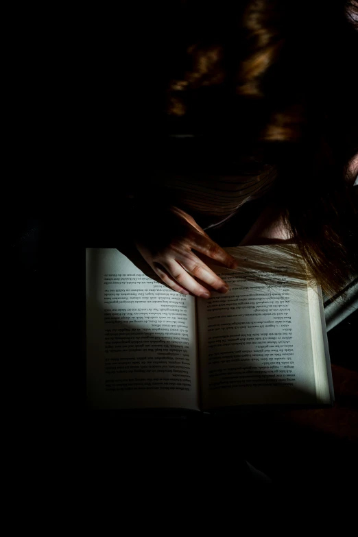 a girl is reading her book in the dark