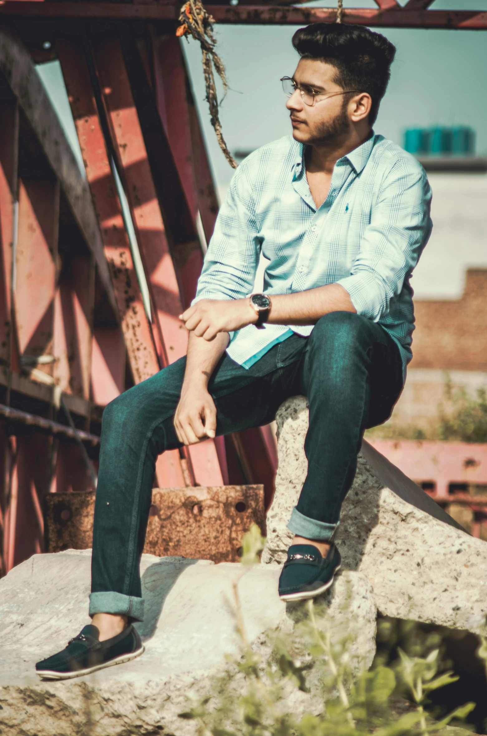 man sitting on large rock looking off in distance