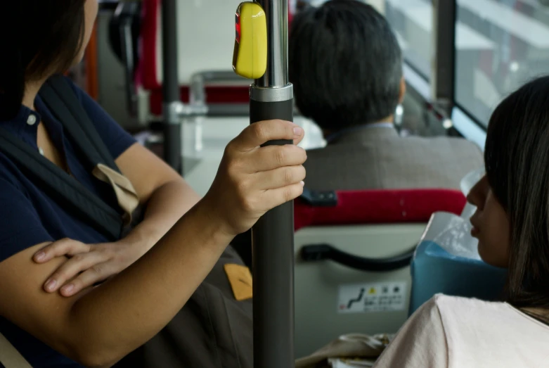 two people are holding the handles of the public bus