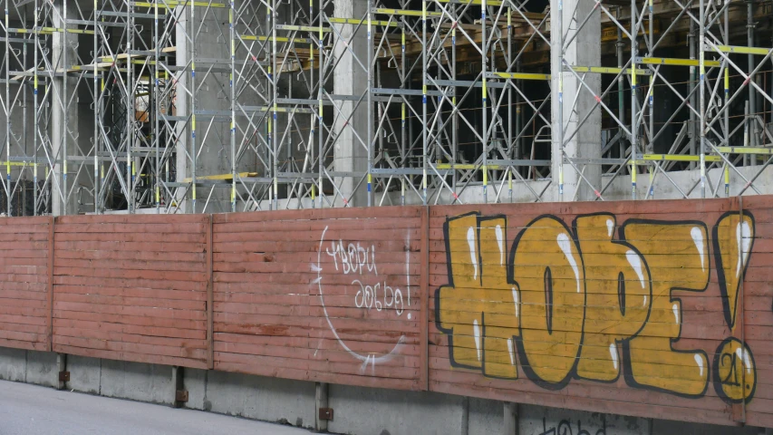graffiti adorns the side of a red brick building under construction