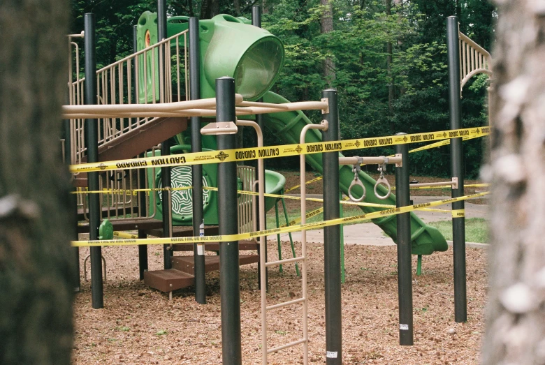 a very pretty green playground structure surrounded by yellow tape