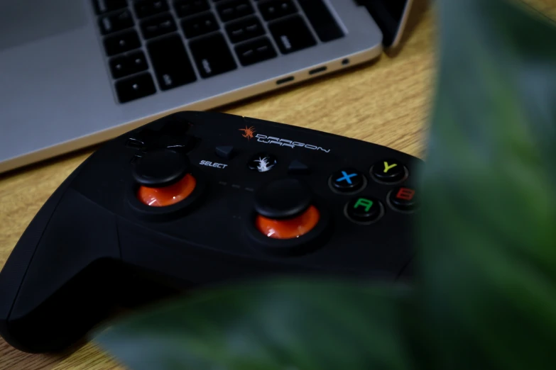 a video game controller on a table next to a laptop