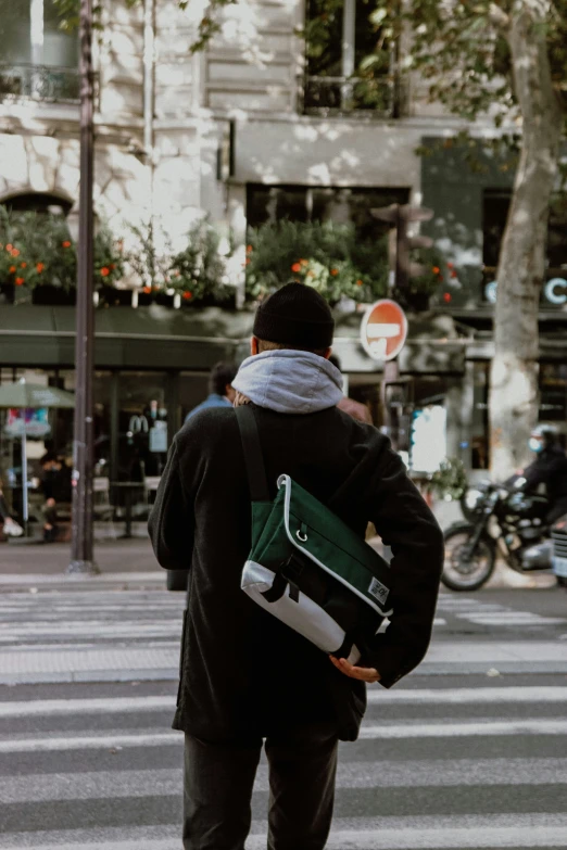 there is a man walking down the street carrying a green bag