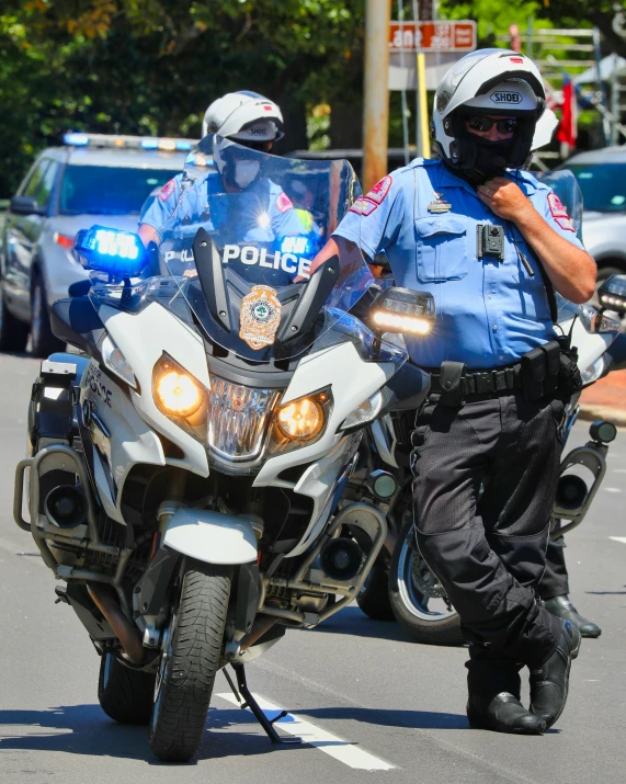 an officer standing on the back of a motorcycle with two police officers in the background