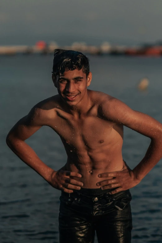 man in wetsuit standing by the water and looking to camera