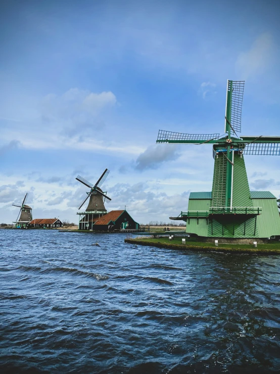 an image of windmills near the water on the beach