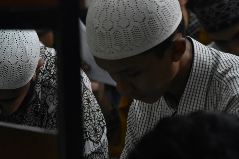 two muslim men in white hats and patterned clothes