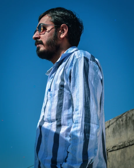 a man with glasses is standing near a wall