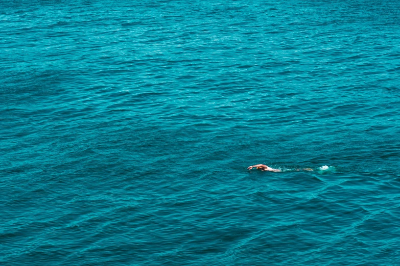 a person floating down on their stomach in the blue ocean