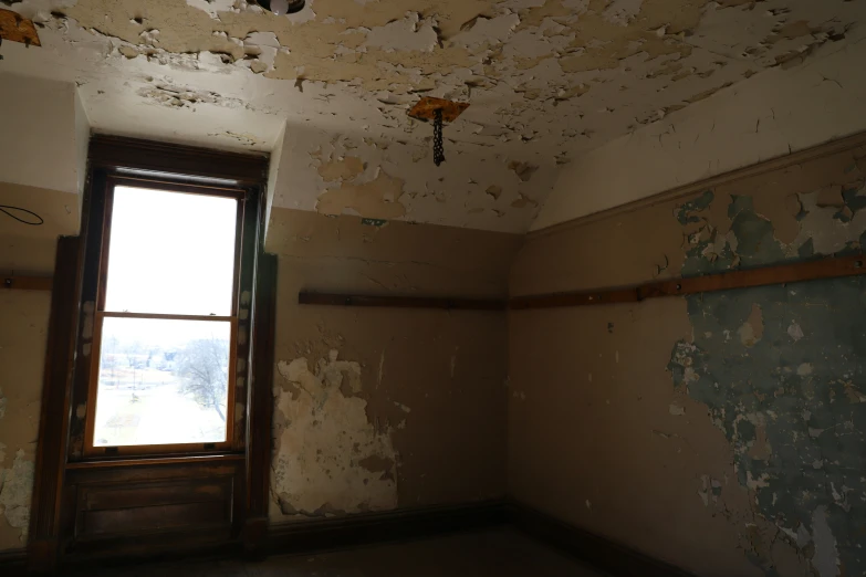 a dilapidated room with many stains and a window