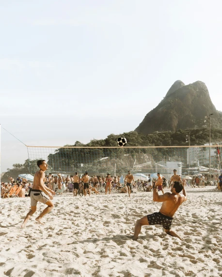 two men playing beach volleyball on a sandy beach