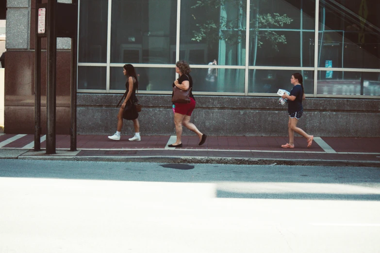 a man and woman walk down the street past some buildings