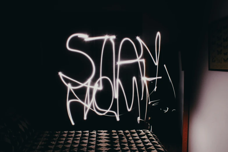 the word'stay calm'is spray painted in white on a black wall behind a bed