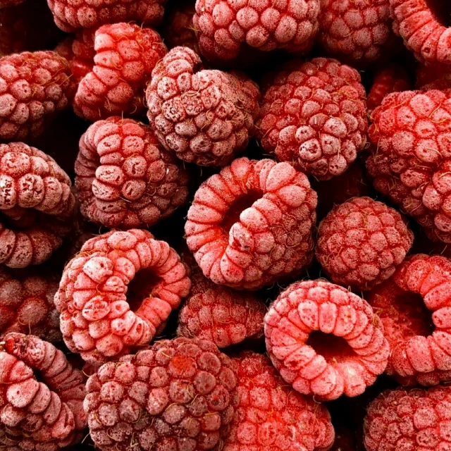 raspberries covered in some red liquid on the surface