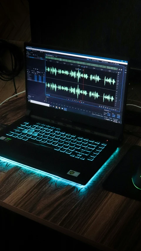 a laptop on a desk with a sound recording applique lit on