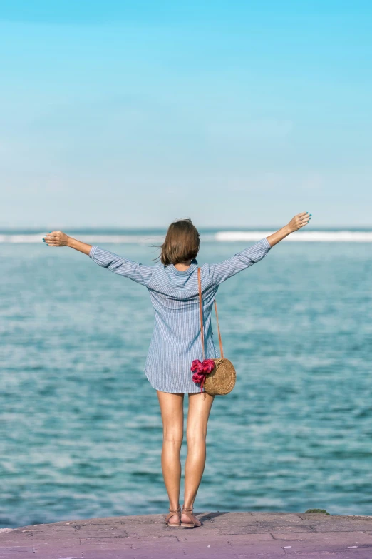 a woman standing on a beach in front of the ocean with her arms outstretched