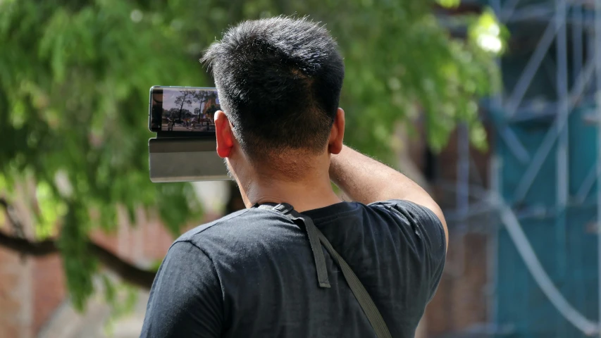 a man in black shirt holding up a camera