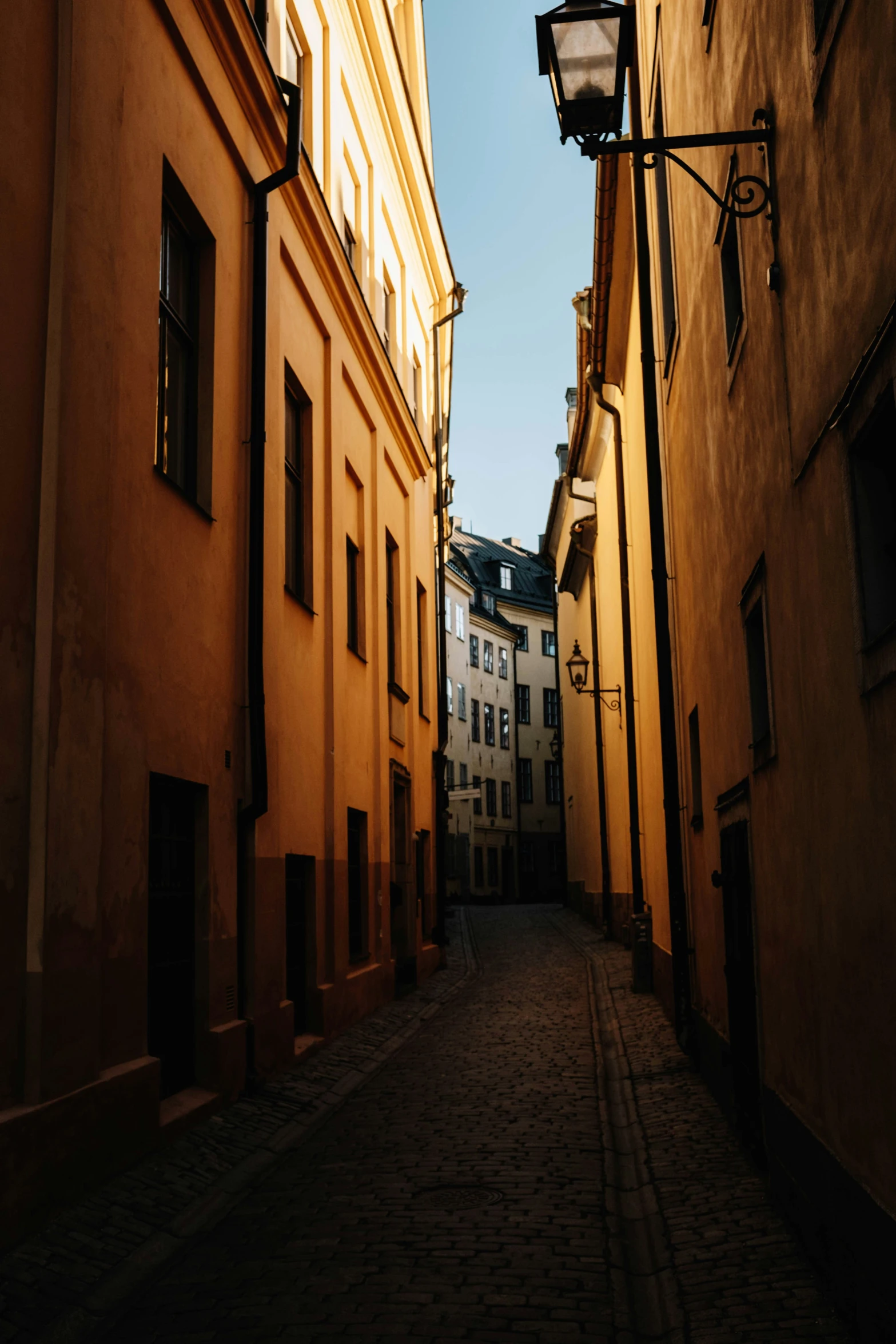 a narrow cobbled street in a city area with the sunlight peeking out