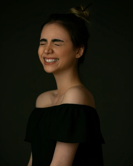 a woman smiling in black dress with a topknot