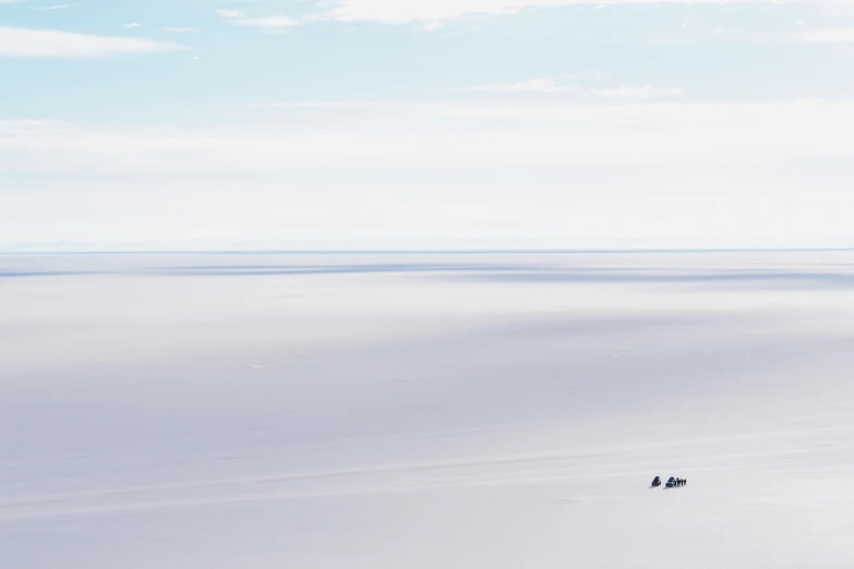 some white snow and two people are walking across the distance