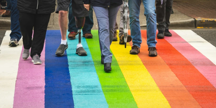 people are walking along a rainbow colored sidewalk