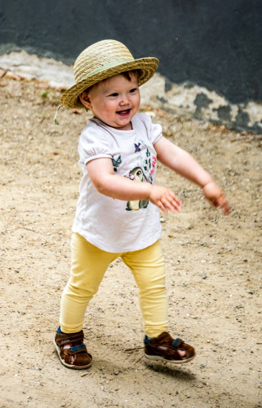 a child playing with a tennis ball on a dirt field